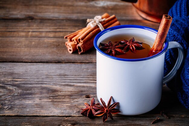 Thé chaud d'automne aux épices cannelle et anis dans une tasse sur fond de bois foncé