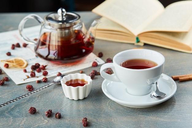 Thé chaud dans une théière et une tasse en verre, sur la table