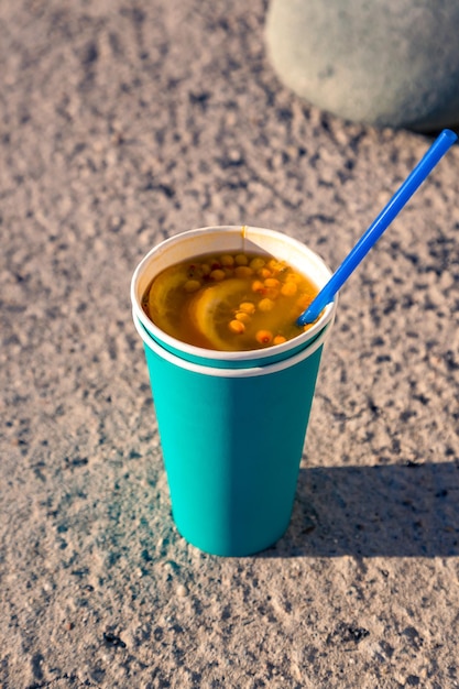 Thé chaud vitaminé à l'argousier et aux oranges dans une tasse en papier