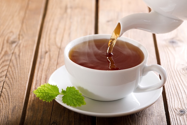 Thé coulant de la théière dans une tasse