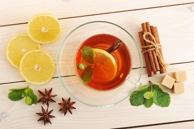 Thé dans une tasse transparente avec des feuilles de citron, de cannelle et de menthe