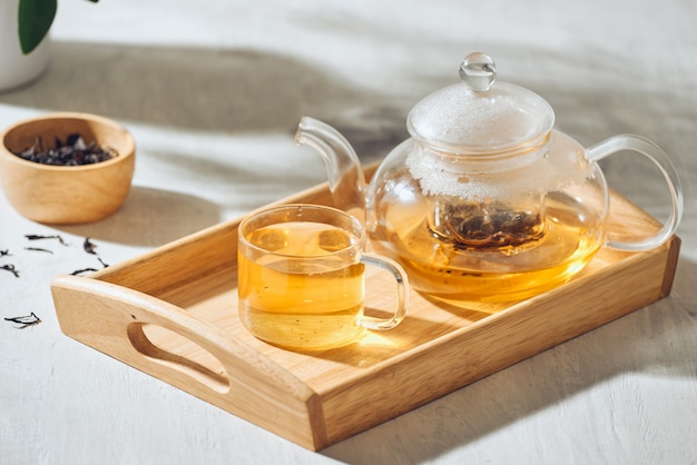 Thé dans une tasse transparente et théière sur un fond en bois