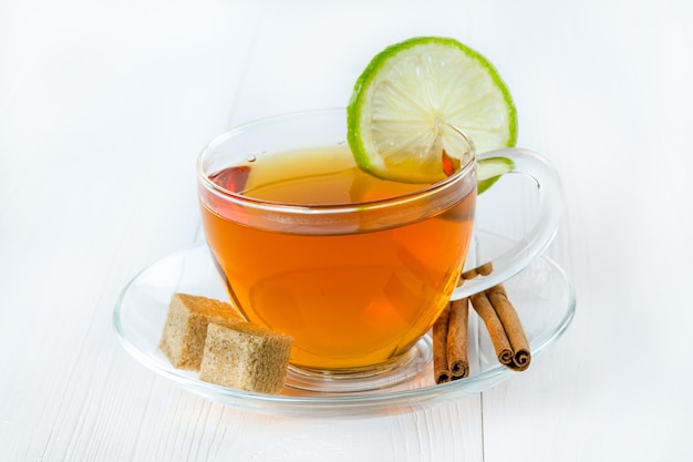 Thé dans une tasse en verre avec citron vert et bâton de cannelle