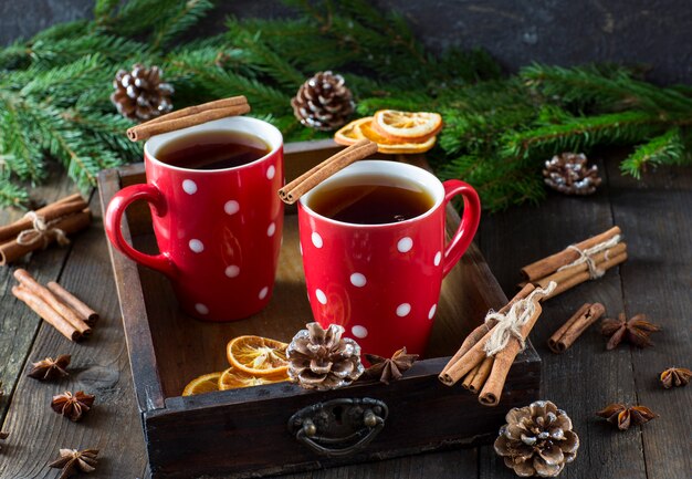 Thé dans des tasses rouges et des branches d'épinette, cônes