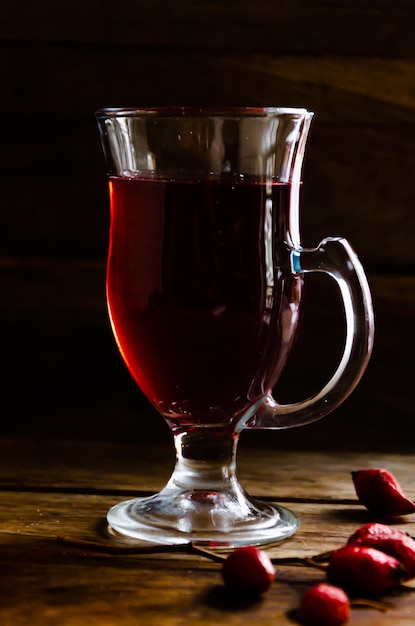 Thé d'églantier dans une tasse en verre sur un fond en bois.