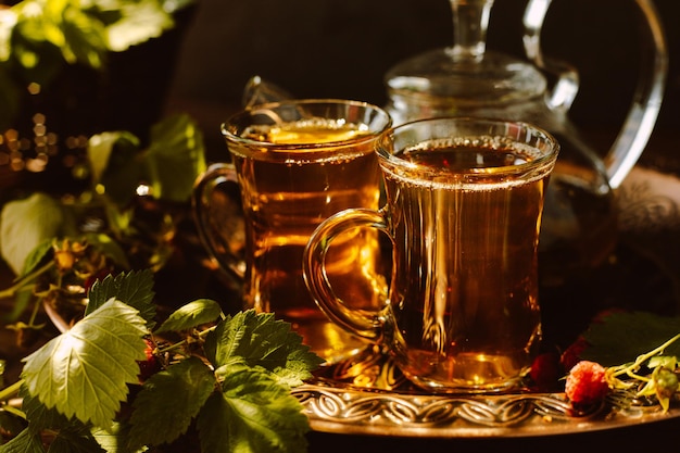 Le thé est versé dans des tasses en verre Une théière et une tasse de thé sur un plateau en cuivre