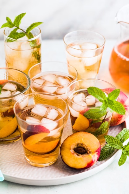 Thé d'été froid avec pêche et menthe dans des verres sur la table