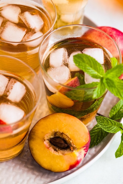 Thé d'été froid avec pêche et menthe dans des verres sur la table