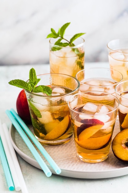 Thé d'été froid avec pêche et menthe dans des verres sur la table