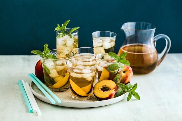 Thé d'été froid avec pêche et menthe dans des verres sur la table