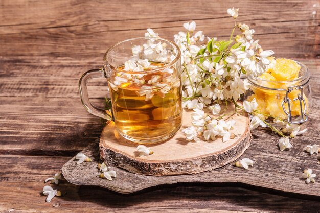 Thé de fleurs d'acacia. Boisson vitaminée saine d'été, lumière dure, ombre sombre. Miel doux, vieux supports en bois, espace de copie