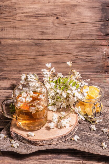 Thé de fleurs d'acacia. Boisson vitaminée saine d'été, lumière dure, ombre sombre. Miel doux, vieux supports en bois, espace de copie