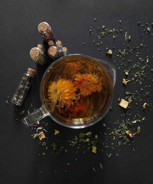 Thé en fleurs dans une théière transparente sur fond sombre