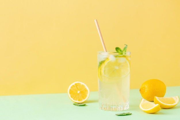 Thé glacé au citron avec feuilles de menthe sur fond bicolore jaune et vert