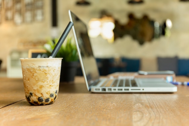 Thé Glacé Au Lait Perlé Avec Ordinateur Portable Sur Une Table En Bois Au Café.