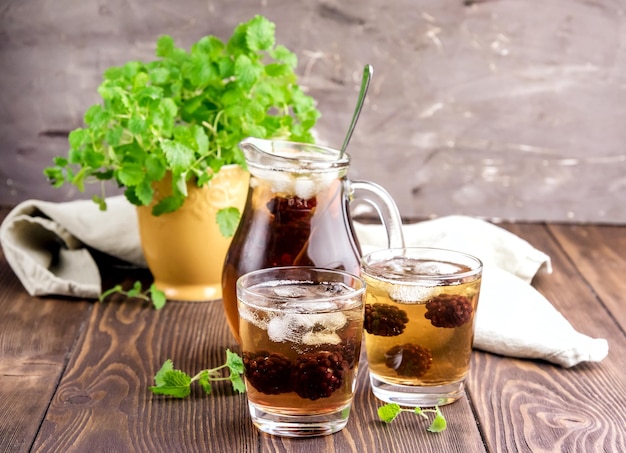 Thé glacé aux baies et à la menthe fraîche dans des verres Fond en bois