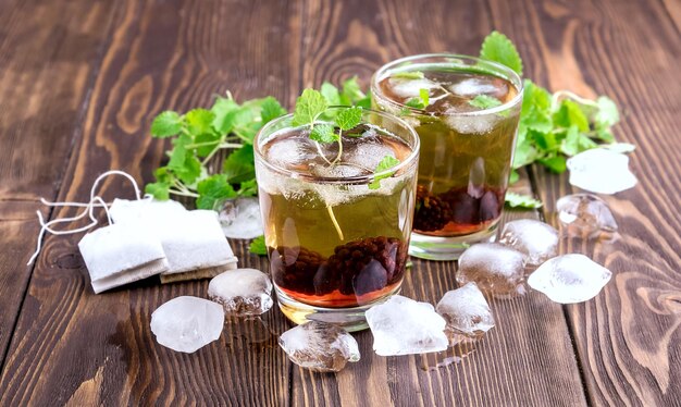 Thé glacé aux baies et à la menthe fraîche dans des verres Fond en bois