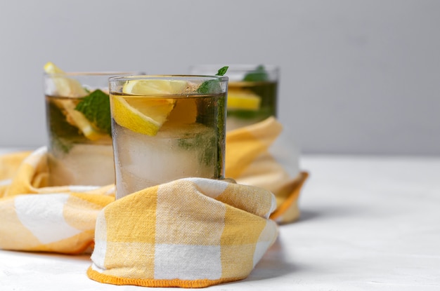 Thé avec glace, menthe et quartiers de citron sur tableau blanc