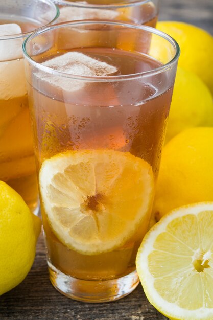 Thé glacé rafraîchissant en verre au citron sur une table en bois