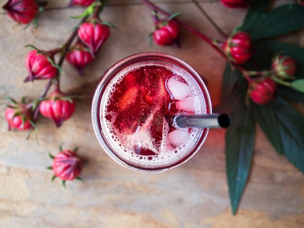 Thé glacé à la roselle avec des fruits frais à la roselle en vue de dessus sur une table en bois