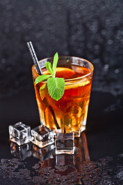 Thé glacé traditionnel avec citron, feuilles de menthe et glaçons en verre.