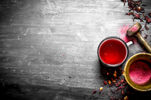 Thé à la grenade écrasé dans un mortier sur une table en bois noir.