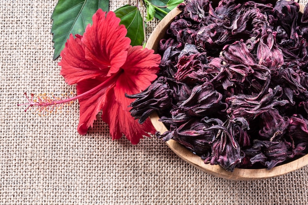 Thé d&#39;hibiscus (Roselle, karkade) dans un bol en bois sur fond de toile de jute avec vue de dessus de fond.