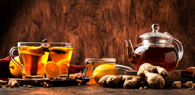 Thé d'hiver noir chaud avec gingembre, miel, citron et épices Boisson de rappel immunitaire dans une tasse en verre sur fond de table en bois rustique espace de copie