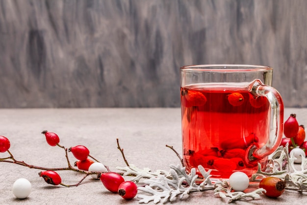 Thé à la hot dog-rose. Boisson d'hiver pour la bonne humeur avec des baies fraîches, des feuilles et des bonbons.