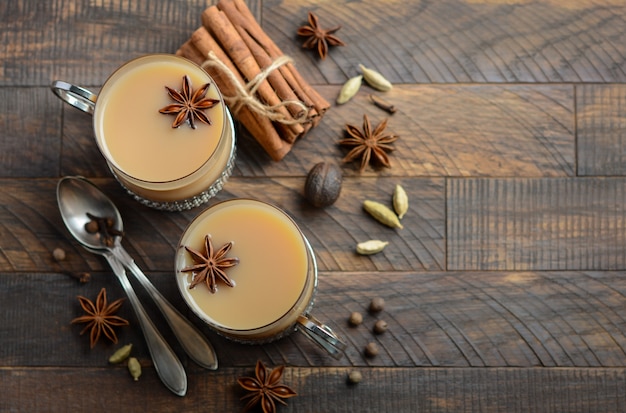 Thé indien masala chai. Thé aux épices avec du lait dans les tasses vintage sur le tabl en bois rustique