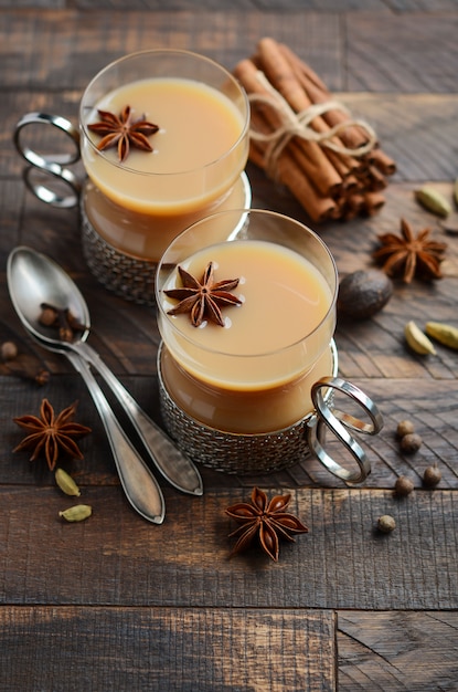 Thé indien masala chai. Thé aux épices avec du lait dans les tasses vintage sur le tabl en bois rustique