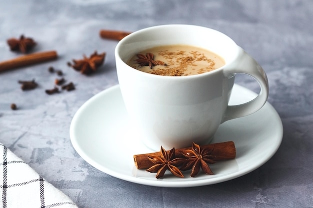 Thé indien masala chai thé épicé masala chai avec du lait et des épices dans une tasse sur fond de pierre grise