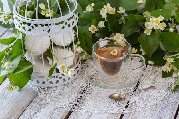 thé avec jasmin et guimauves dans une cage décorative blanche sur une table en bois blanche