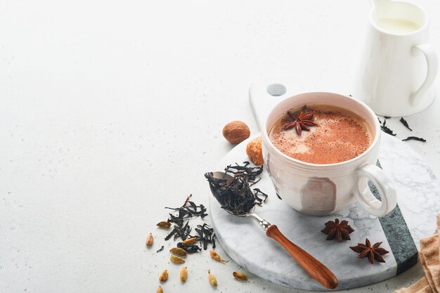 Thé masala Thé épicé masala chai avec du lait et des épices sur fond gris clair Boisson indienne traditionnelle Boisson aux épices Copier l'espace Mise au point sélective