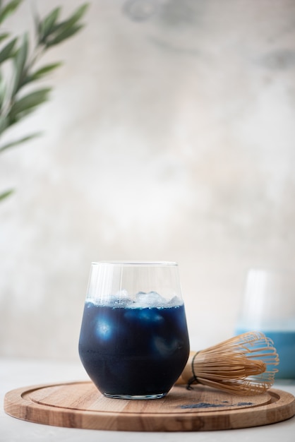 Thé matcha bleu glacé en verre sur une planche de bois