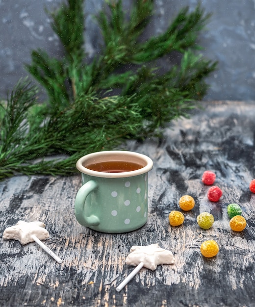 Thé de Noël dans une tasse turquoise avec des pois blancs et des bonbons Boules gommeuses au chocolat blanc et sucette