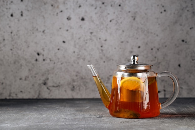 Photo thé noir chaud et sain au citron dans une théière en verre