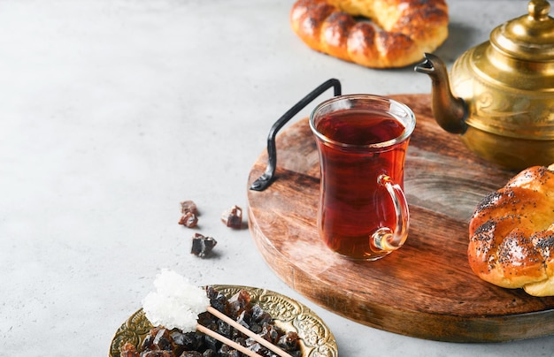 Thé noir turc Tasse en verre de thé noir turc et bagel traditionnel turc croustillant sur fond de table en béton gris Concept de pâtisserie pour le petit déjeuner Boisson chaude brassée traditionnelle turque