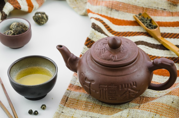 Thé oolong frais de culture asiatique et théière sur fond blanc