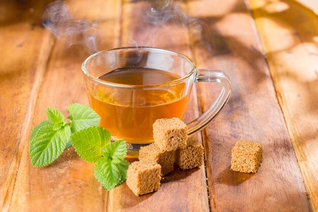 Thé panela de canne dans une tasse en verre sur une surface en bois libre de droits