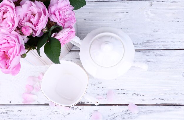 Thé de petit déjeuner avec théière de roses de jardin roses fraîches sur fond de bois de couleur