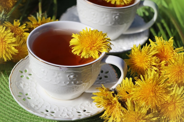 Thé de pissenlit avec une fleur jaune fraîche dans une tasse Boisson vitaminique Thé à base de pissenlit pour la santé