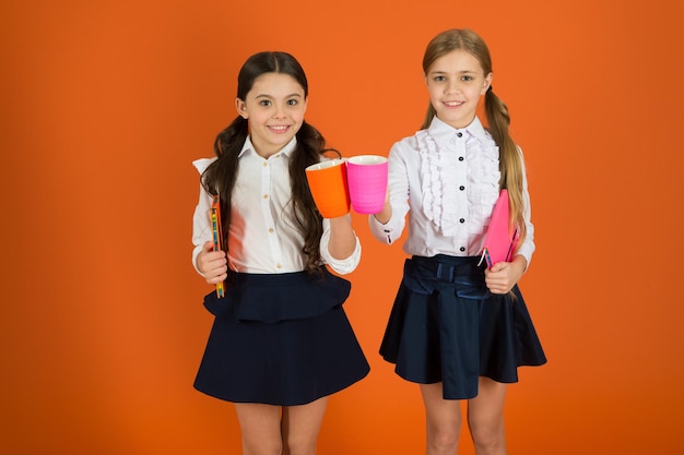 Thé pour deux et deux pour le thé Petits enfants buvant du thé ou du lait du matin Jolies écolières tenant des tasses et des livres Petites filles appréciant le petit déjeuner à l'école Écoliers prenant leur petit déjeuner le matin