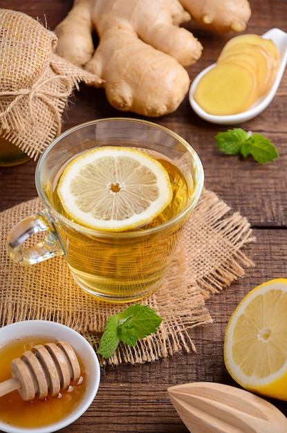 Thé de racine de gingembre au citron et au miel sur une table en bois.