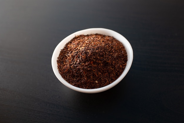 Thé Rooibos sur plaque blanche sur une table en bois.