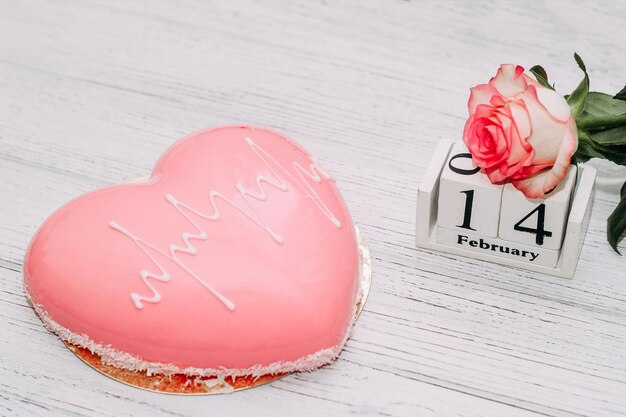 Thé rose rose avec gâteau mousse rose en forme de coeur et calendrier du 14 février