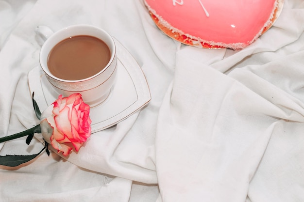 Thé rose rose avec gâteau mousse rose en forme de coeur avec une tasse de café