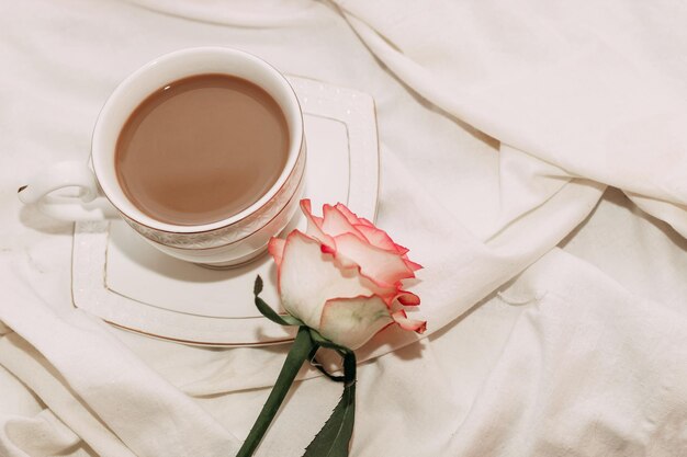 Thé rose rose avec une tasse de café sur le lit