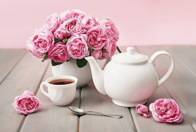 Thé avec des roses roses sur une table en bois gris, espace copie.