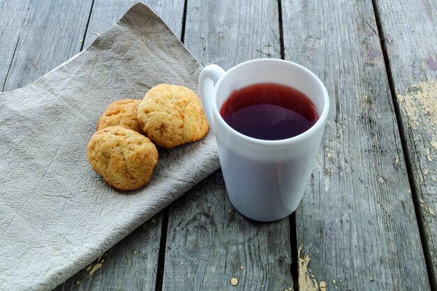 Thé rouge dans une tasse blanche sur une table en bois et biscuits faits maison sur une serviette en lin. Vue d'en-haut